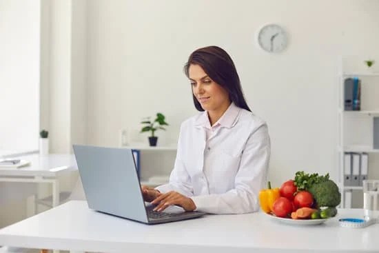 Dietitian Using Laptop Making Diet Plan or Giving Consultation for Clients Online